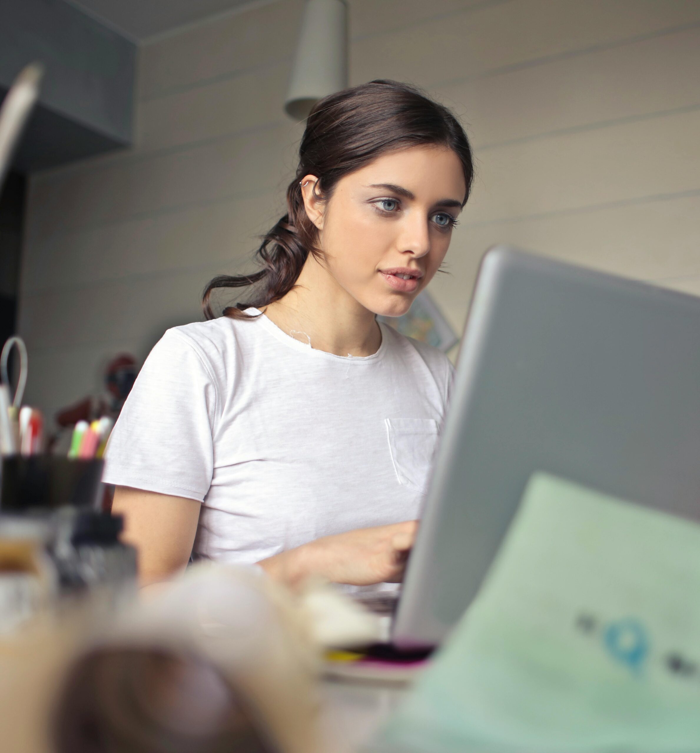 Young woman attentively working on her laptop in a cozy indoor setting.